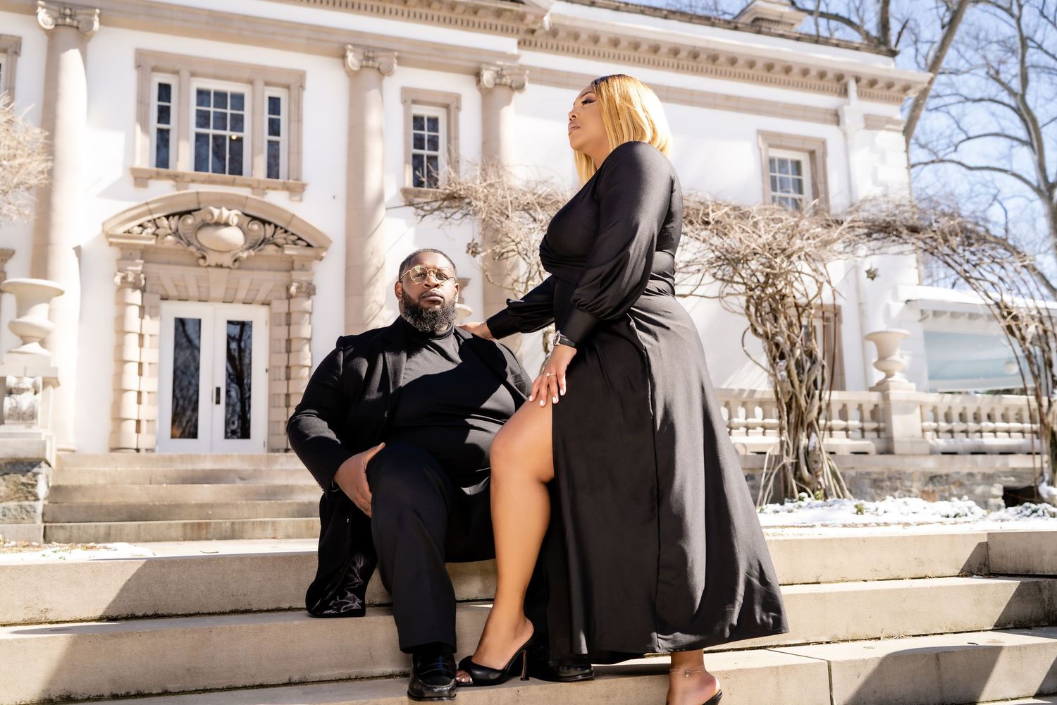 Romantic couple posing on steps of grand historic mansion.
