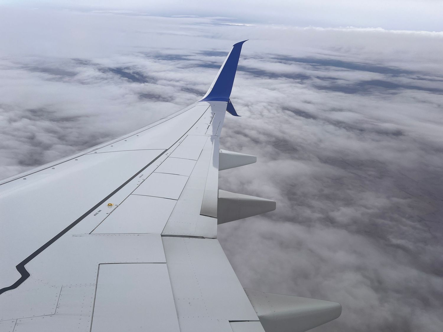 Aerial view of airplane wing against cloudy sky during flight.
