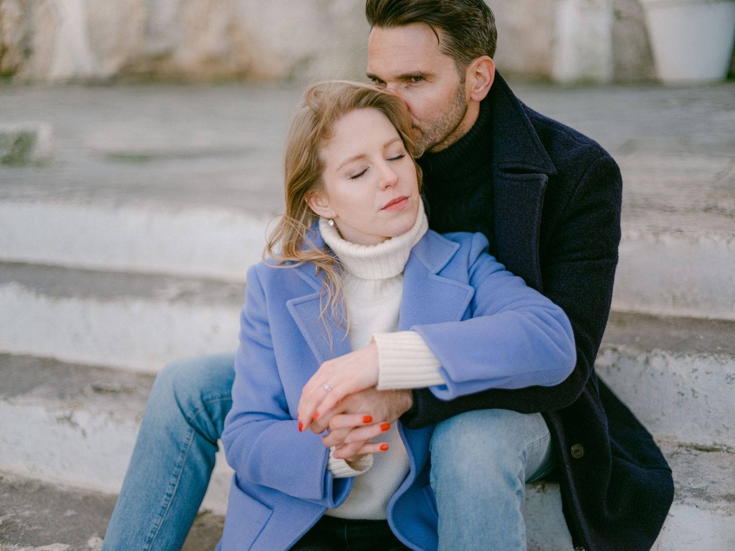 Un couple en tenue décontractée d’hiver partage un moment intime en plein air.