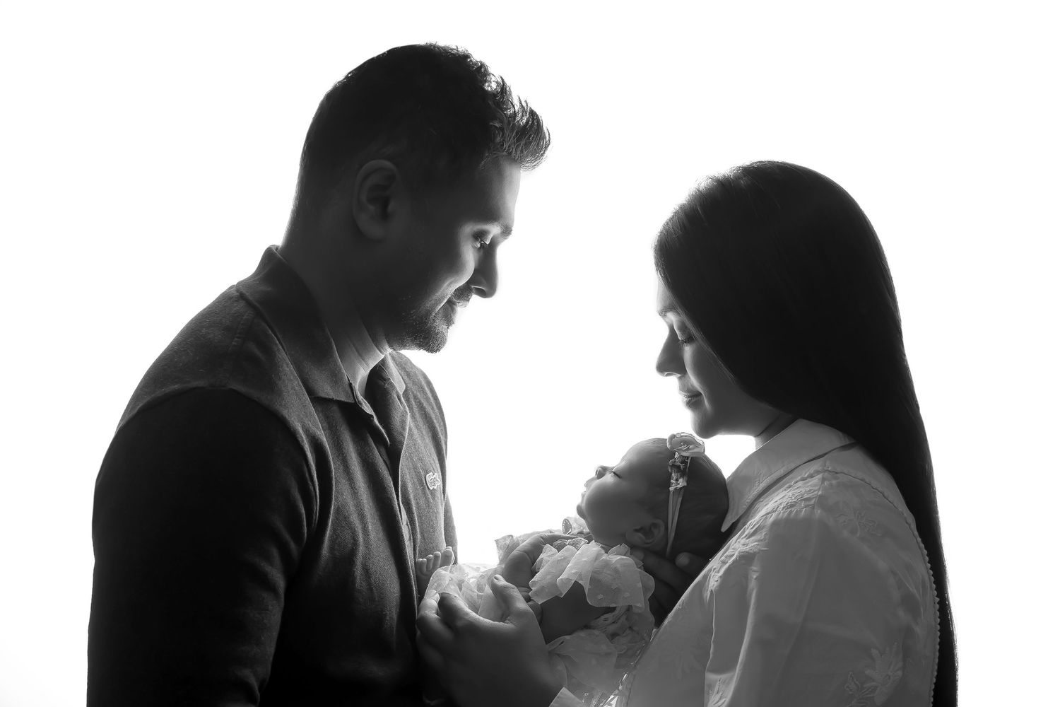 Classic black and white silhouette of a family embracing their newborn, preserving a precious memory.