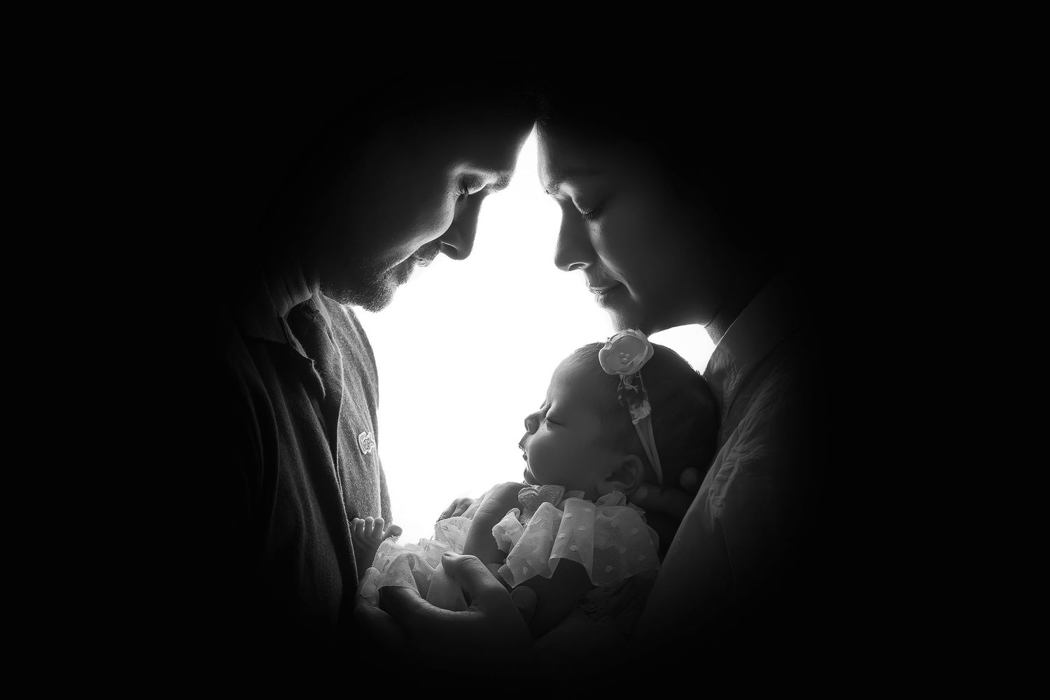 Minimalist black and white silhouette of a baby in parents' arms, showcasing the beauty of new life.