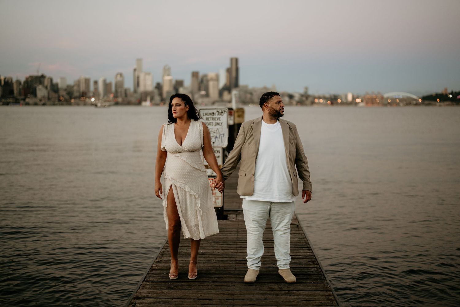 Hispanic couple posing on the dock at Alki Beach for engagement photos