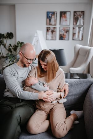 Tender family moment on grey couch with photo gallery wall in background.