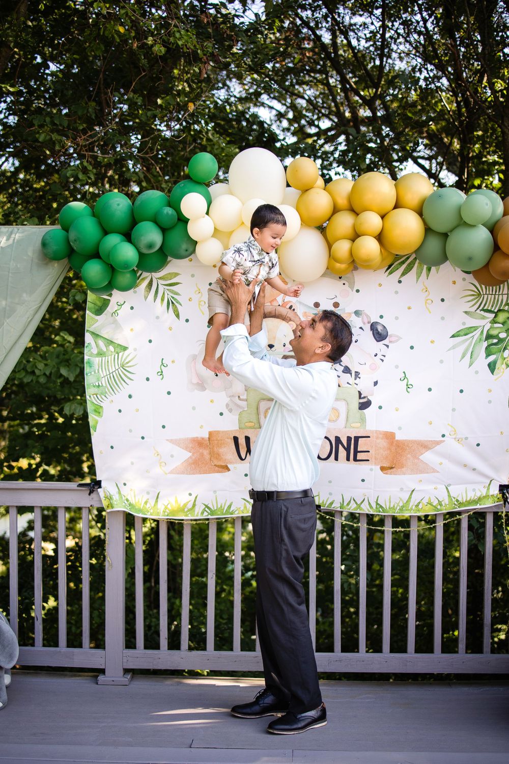 A celebration scene with green and yellow balloon arch and confetti backdrop.