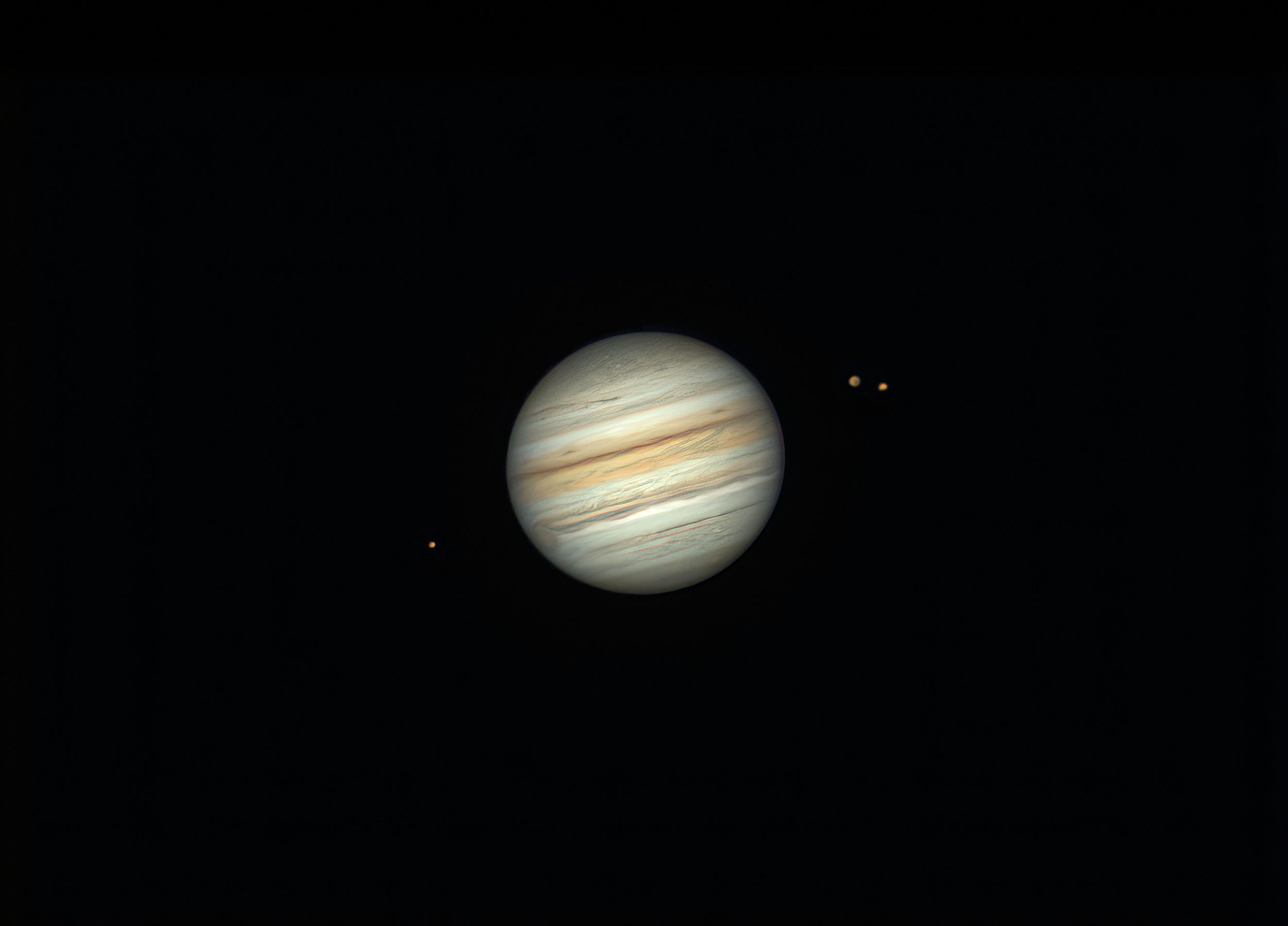 Jupiter and its moons photographed against the darkness of space.