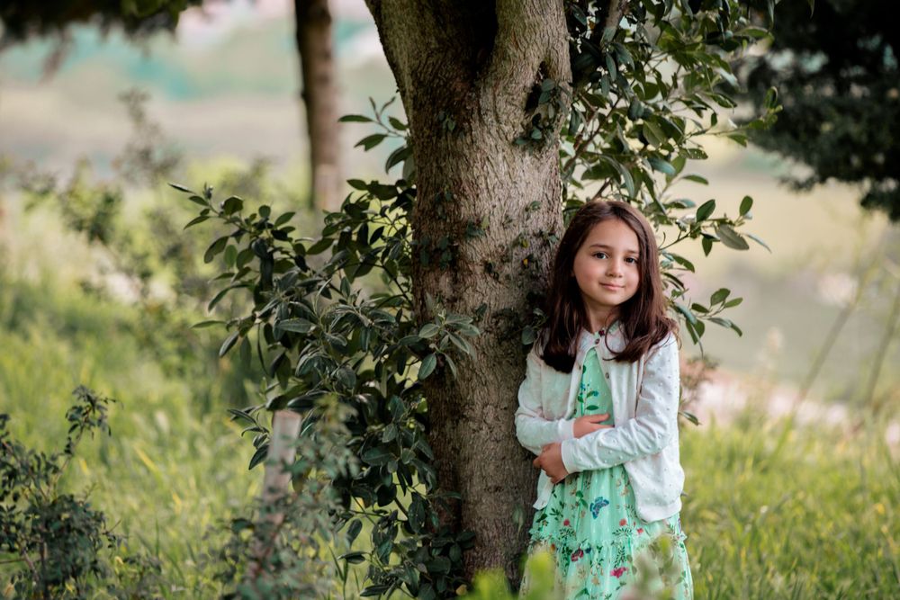 Child in mint green dress exploring wooded area during outdoor photoshoot.