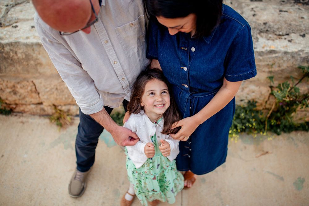 Family photo session outdoors with red balloon and casual attire.