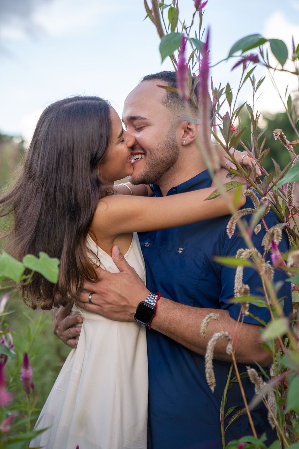 A romantic couple embracing among purple flowers in a garden setting.