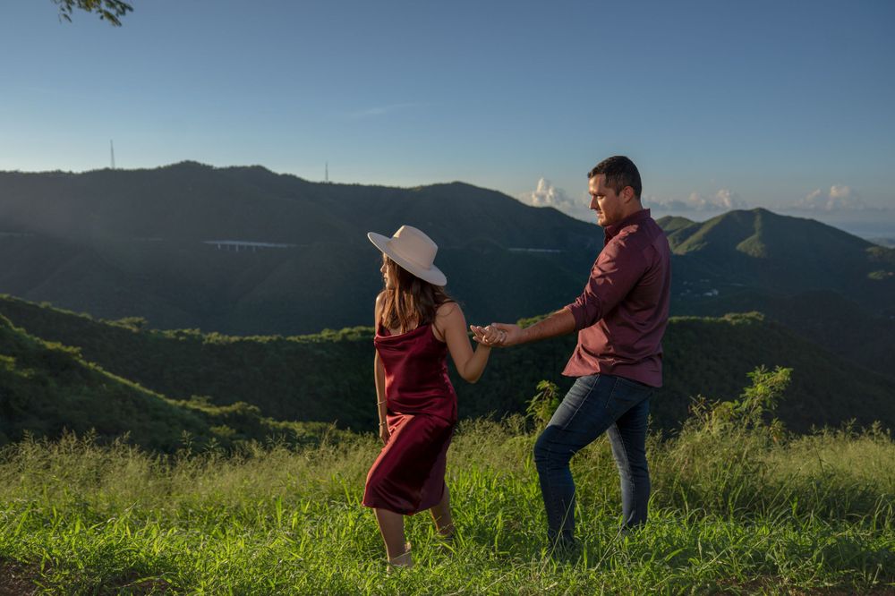 A couple dancing together on a hilltop with mountain views in the background.