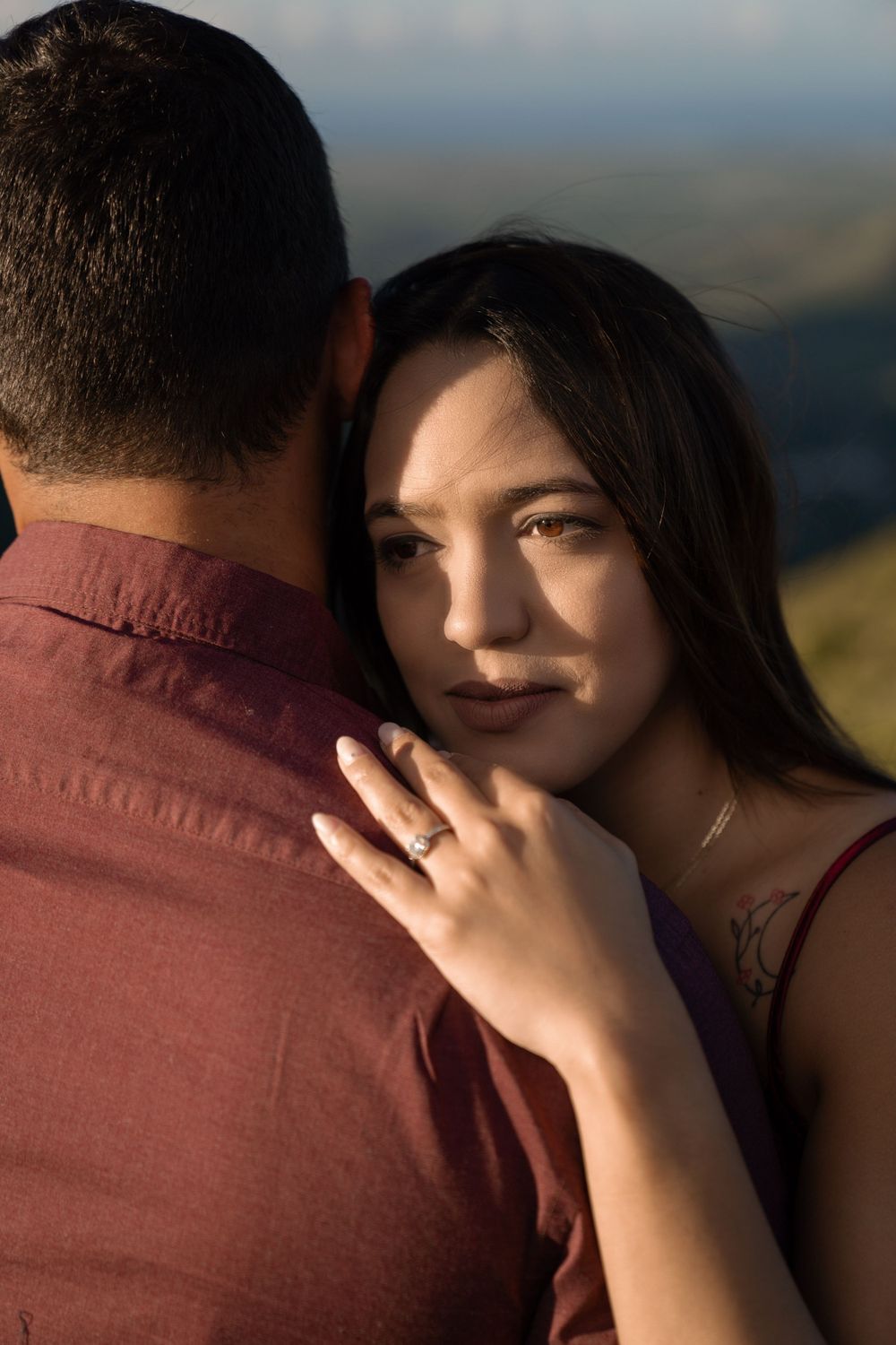 A couple sharing an intimate moment against a scenic mountain backdrop at sunset.