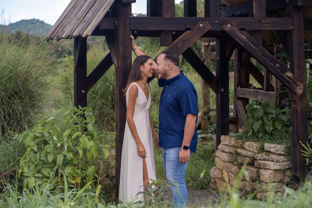 Romantic couple sharing tender moment under rustic wooden structure.