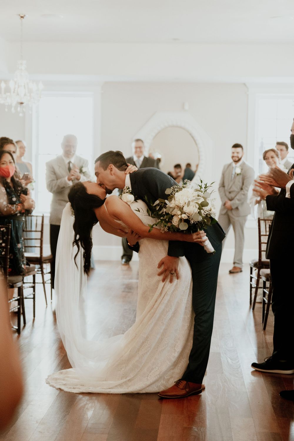 Romantic wedding dance dip on white dance floor with guests watching.