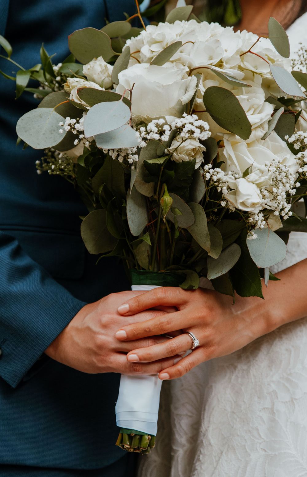 Close-up of white wedding bouquet with eucalyptus leaves and delicate flowers.