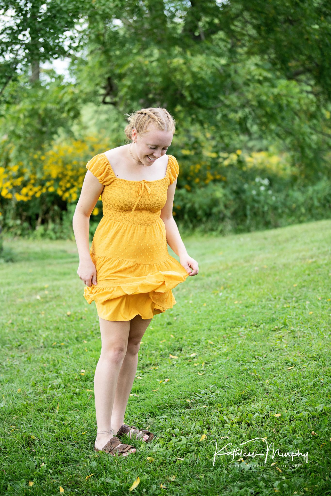 Person in a bright yellow sundress wearing sandals on green grass with summer wildflowers in the background.