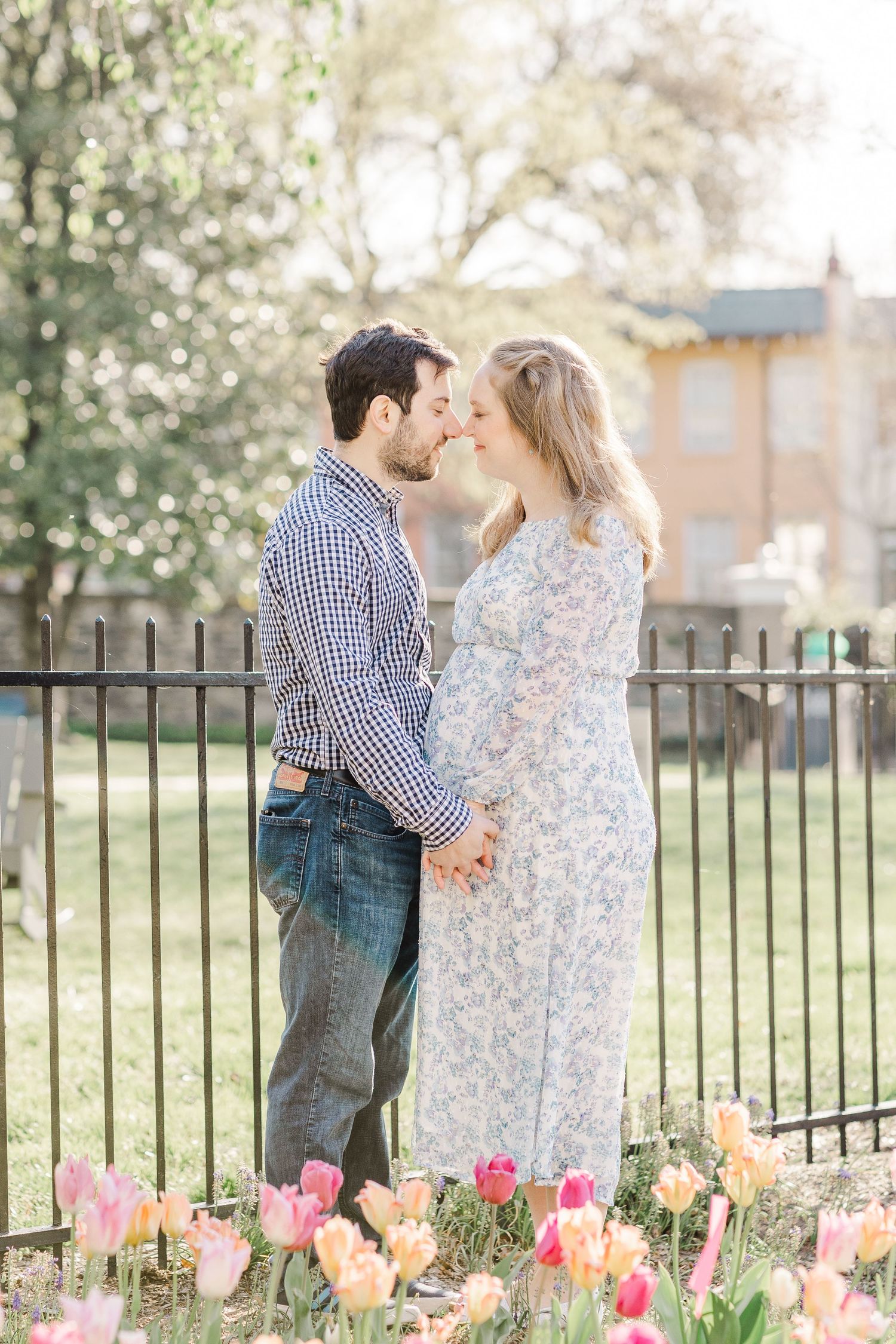 A romantic spring photoshoot with tulips blooming in a garden setting with a wrought iron fence.