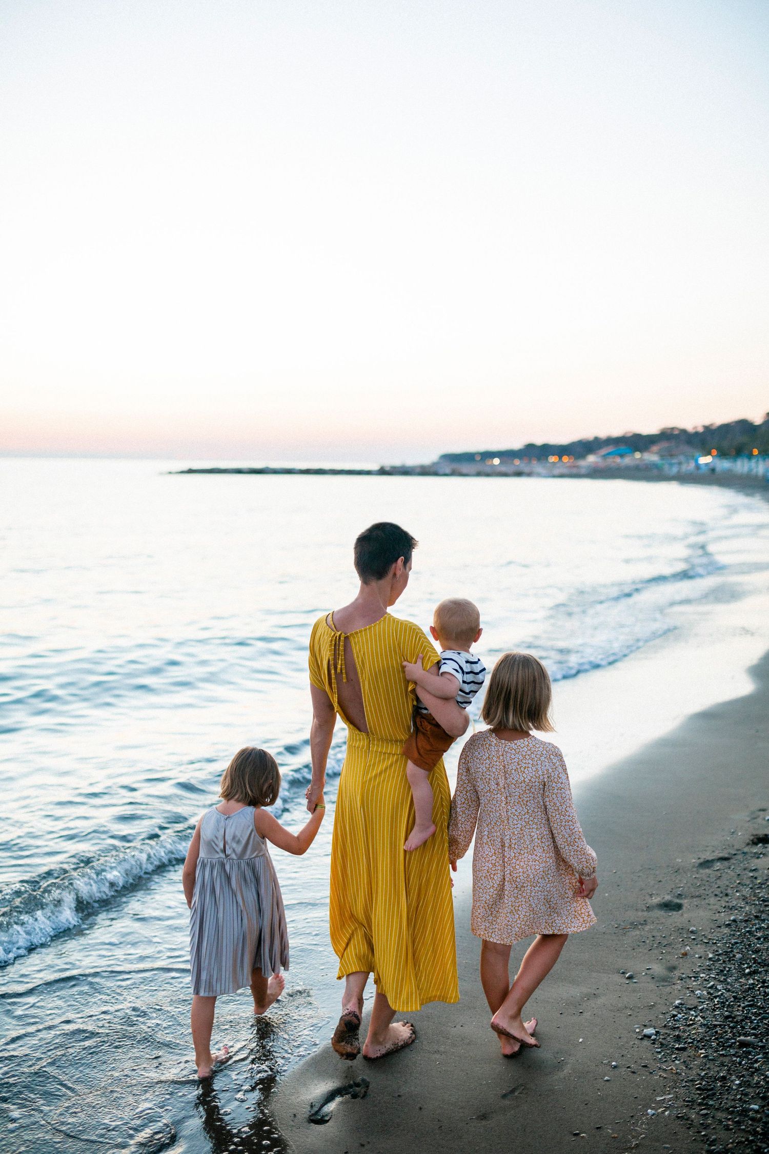 People walking together along beach at sunset with waves lapping at shore.