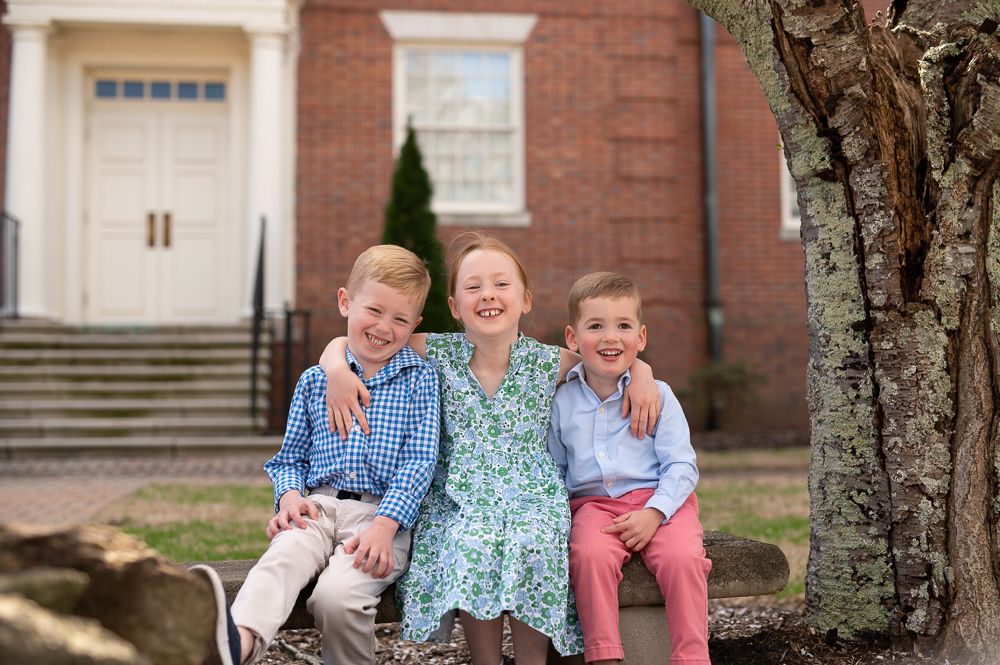 Family group photo taken outside a brick building on a sunny day.