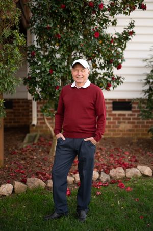 Outdoor portrait series with red camellia bush and brick wall background.
