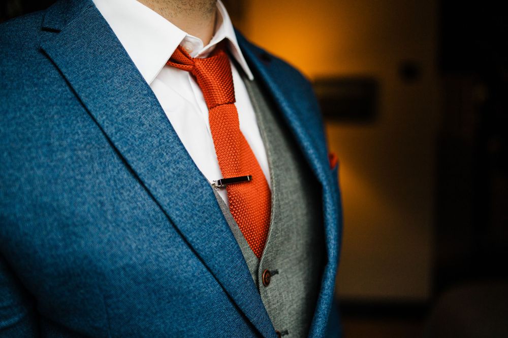 Detail of navy suit jacket with red tie and white shirt.