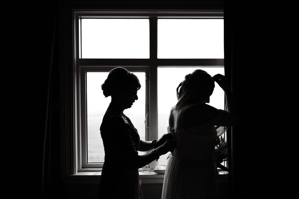Silhouette of two people preparing by window in black and white.