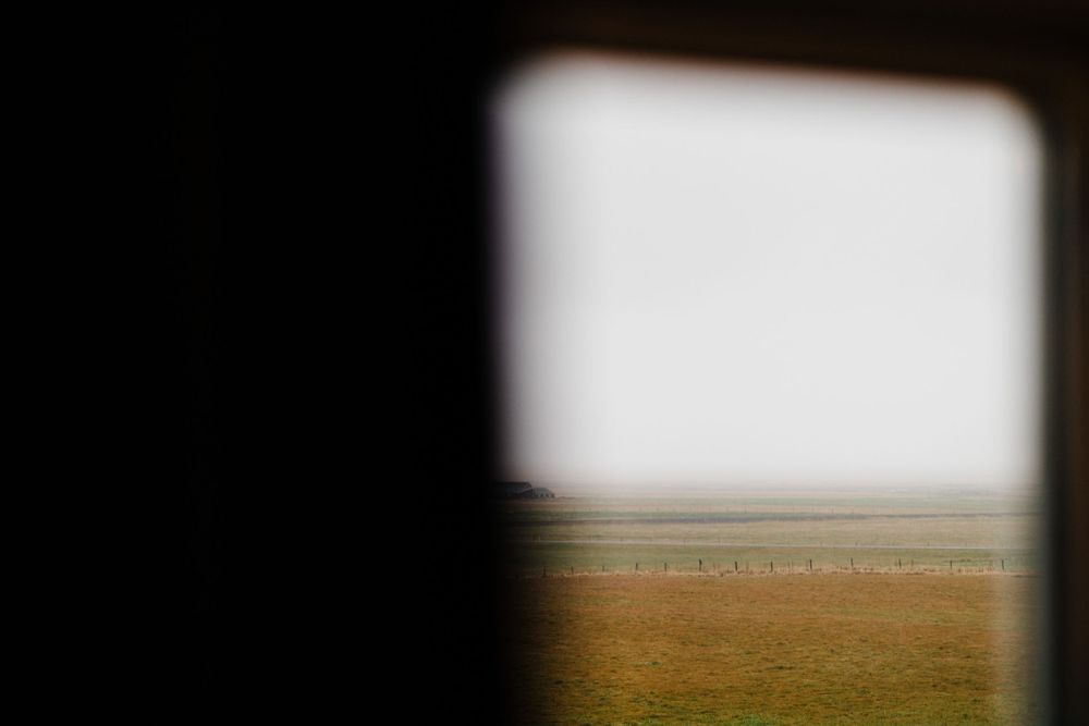 Minimalist view through a window frame of a golden field stretching to the horizon.