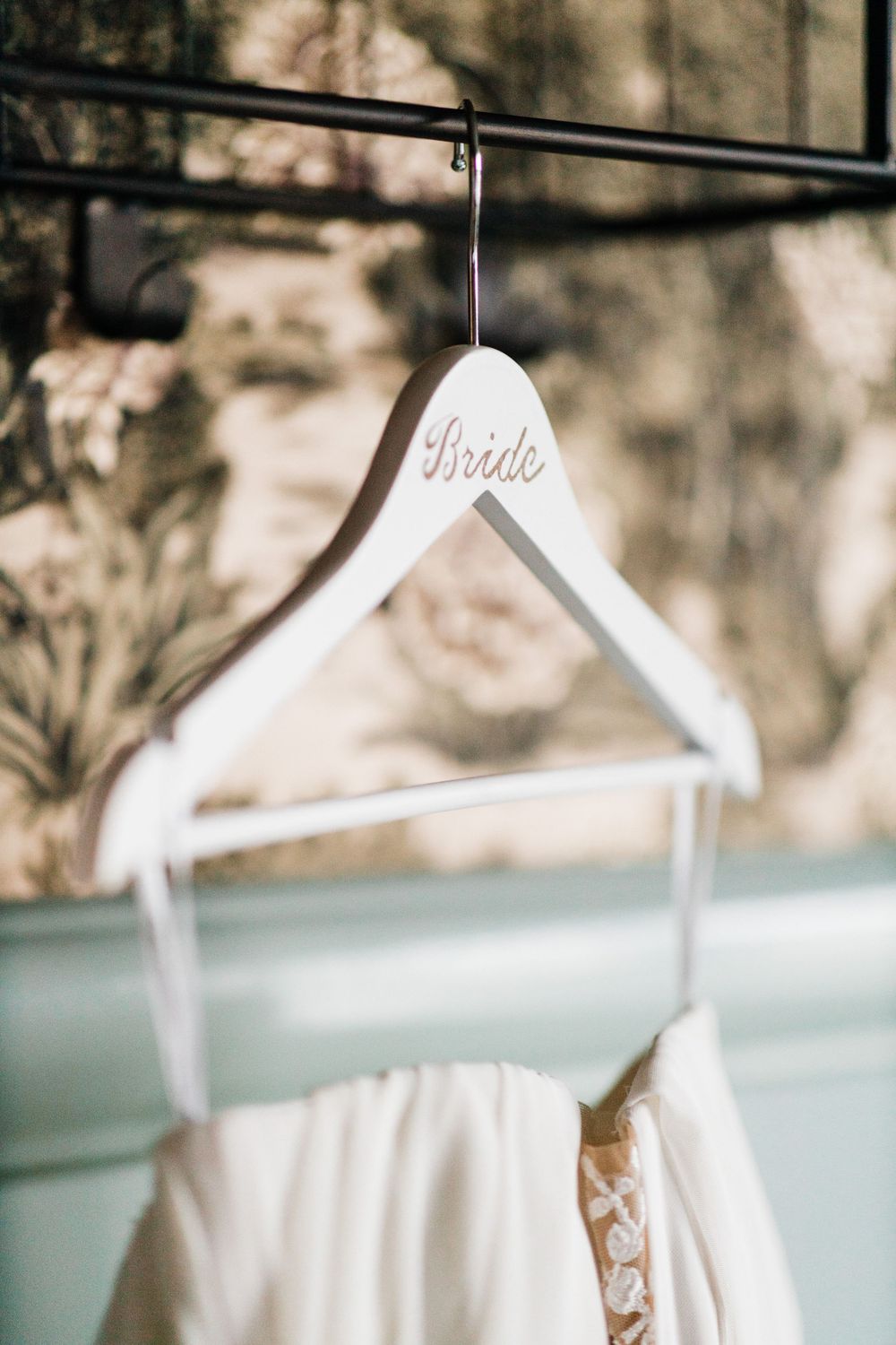 A white wooden wedding dress hanger with 'Bride' text displayed against a soft background.