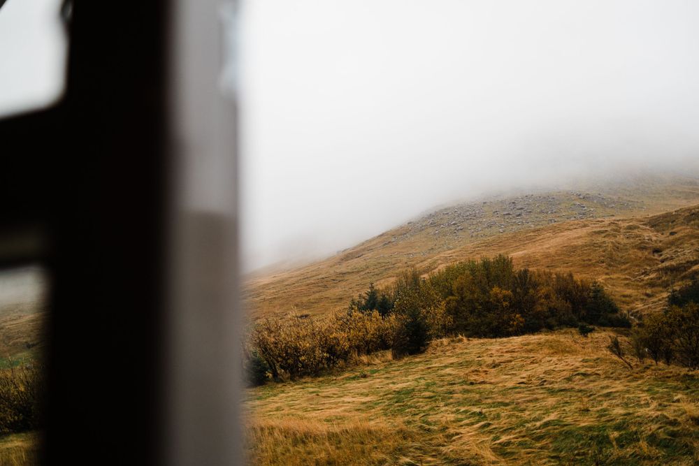 Misty mountain landscape with autumn foliage viewed through window frame.