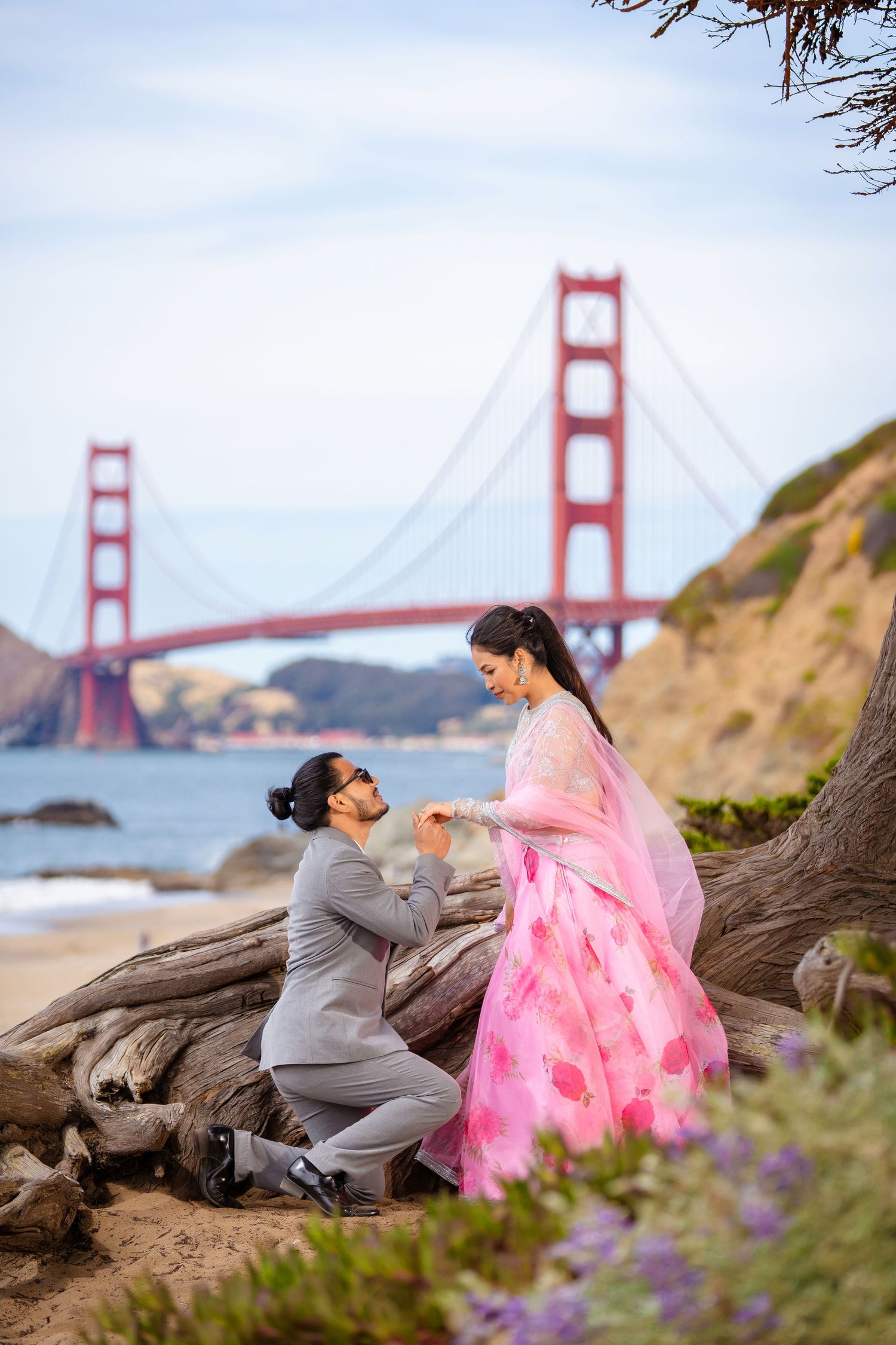 Romantic proposal scene with iconic Golden Gate Bridge backdrop at Baker Beach in San Francisco.