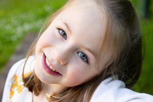 Close up portrait of child smiling outdoors with natural lighting.