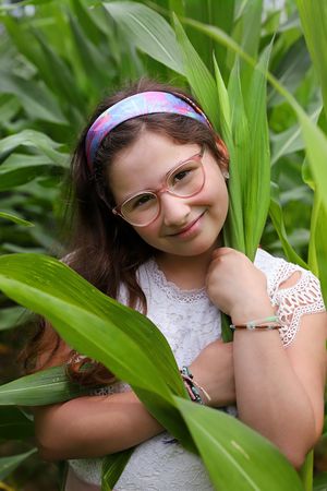 Portrait amid green foliage wearing a lace dress and headband.