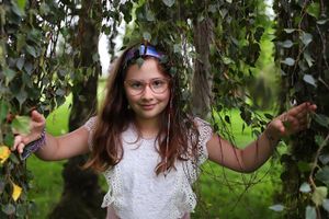 Outdoor portrait surrounded by hanging vines and tropical foliage.