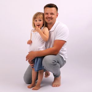 Studio portrait of parent and child in white shirts against light background.