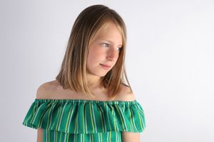 Portrait in green off-shoulder ruffled top against white background.