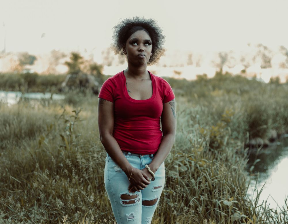 A sunset portrait in a natural setting with tall grass and a calm stream in the background.