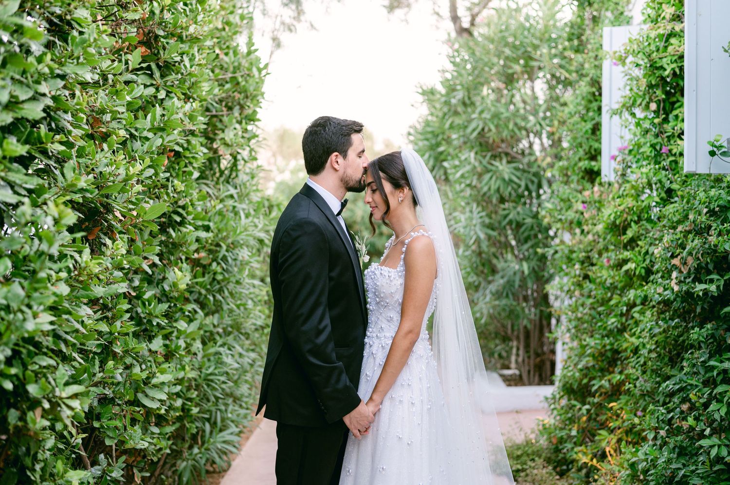 A romantic garden wedding portrait with couple surrounded by lush greenery.