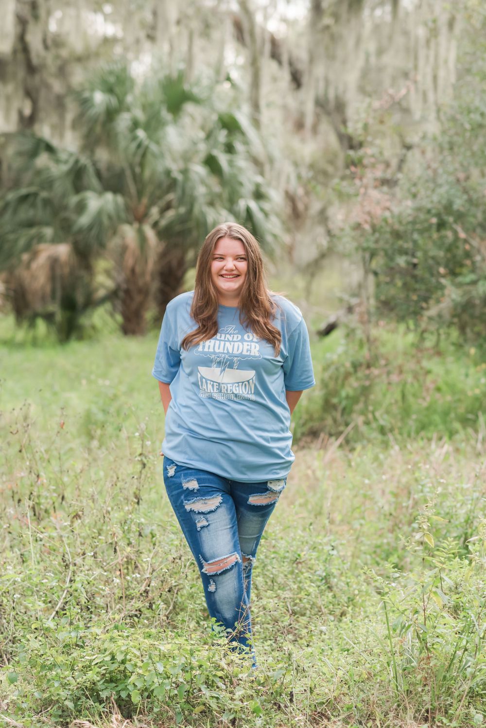 senior girl stands in the tall grass at Circle B Bar Reserve Lakeland, Florida