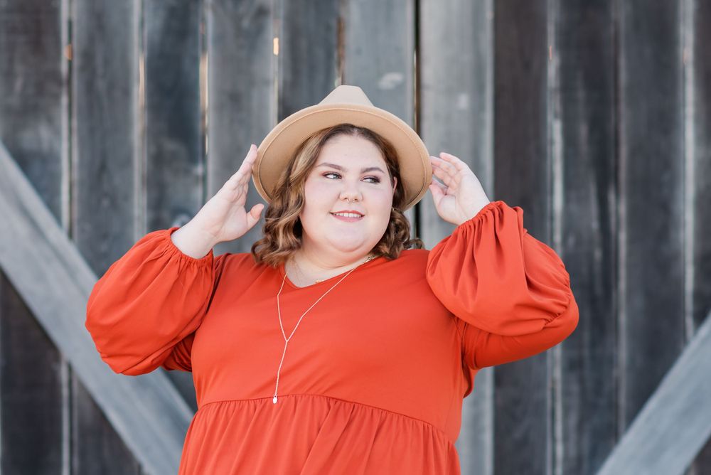senior session girl with wide brim hat stands in front of barn doors in Polk City, Florida The Barn on Heartland Farm
