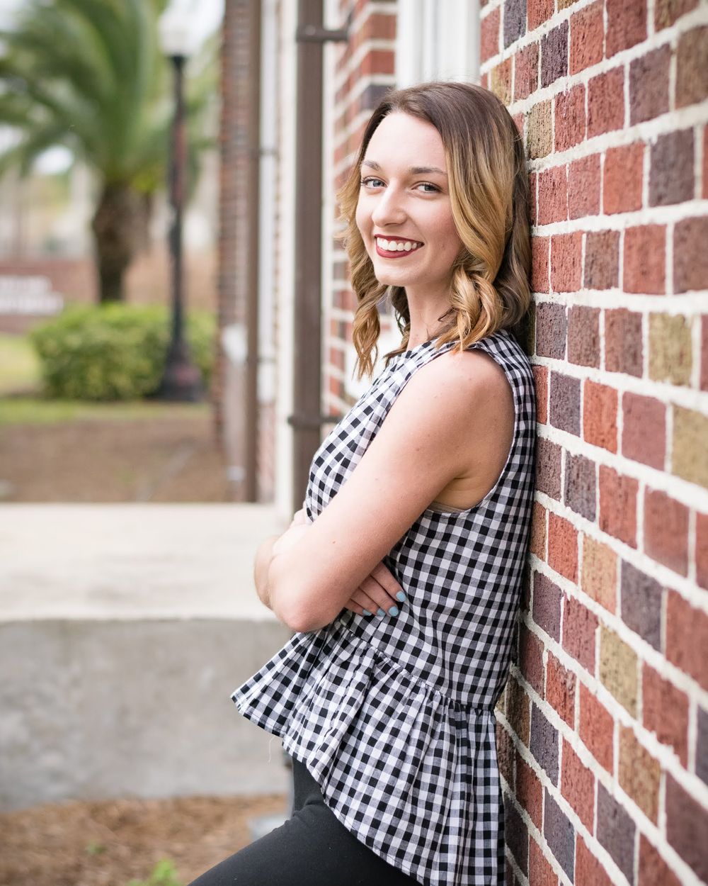 Senior girl leans against brick wall Lakeland Florida Lake Mirror Hollis Gardens Downtown Lakeland