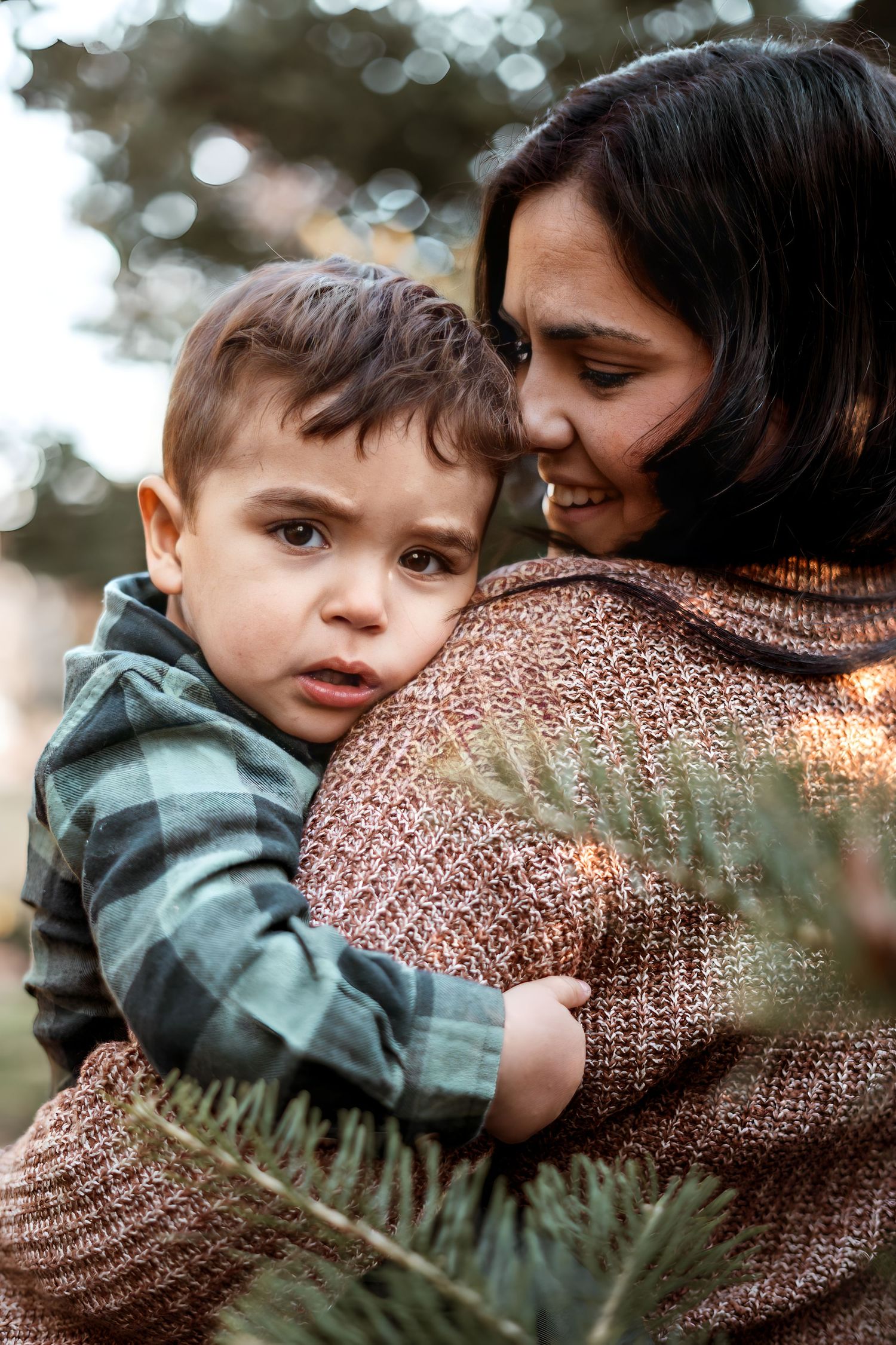 Parent and child sharing tender moment outdoors in soft bokeh lighting.
