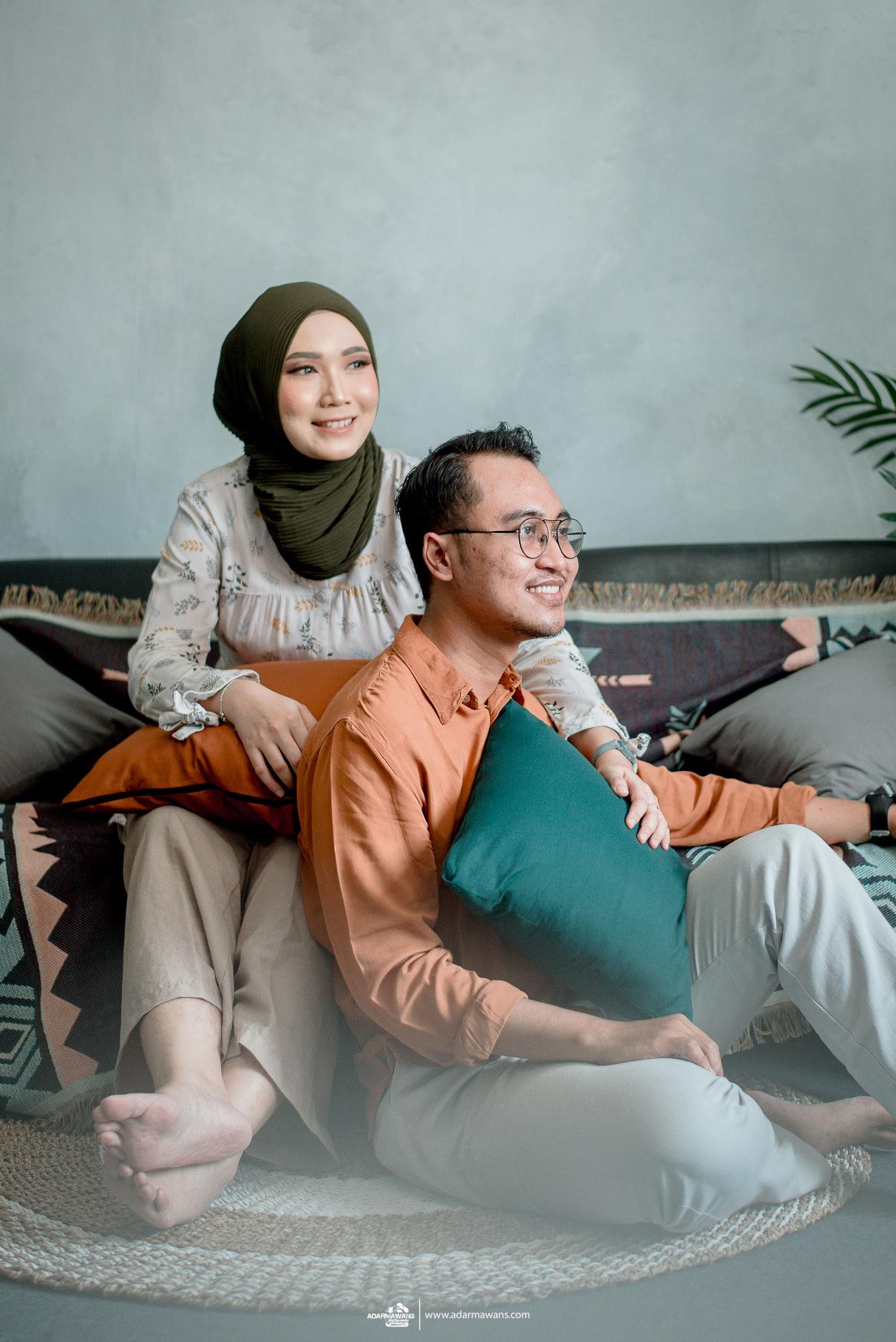 A couple relaxing on floor cushions in a cozy home setting for their lifestyle photoshoot.