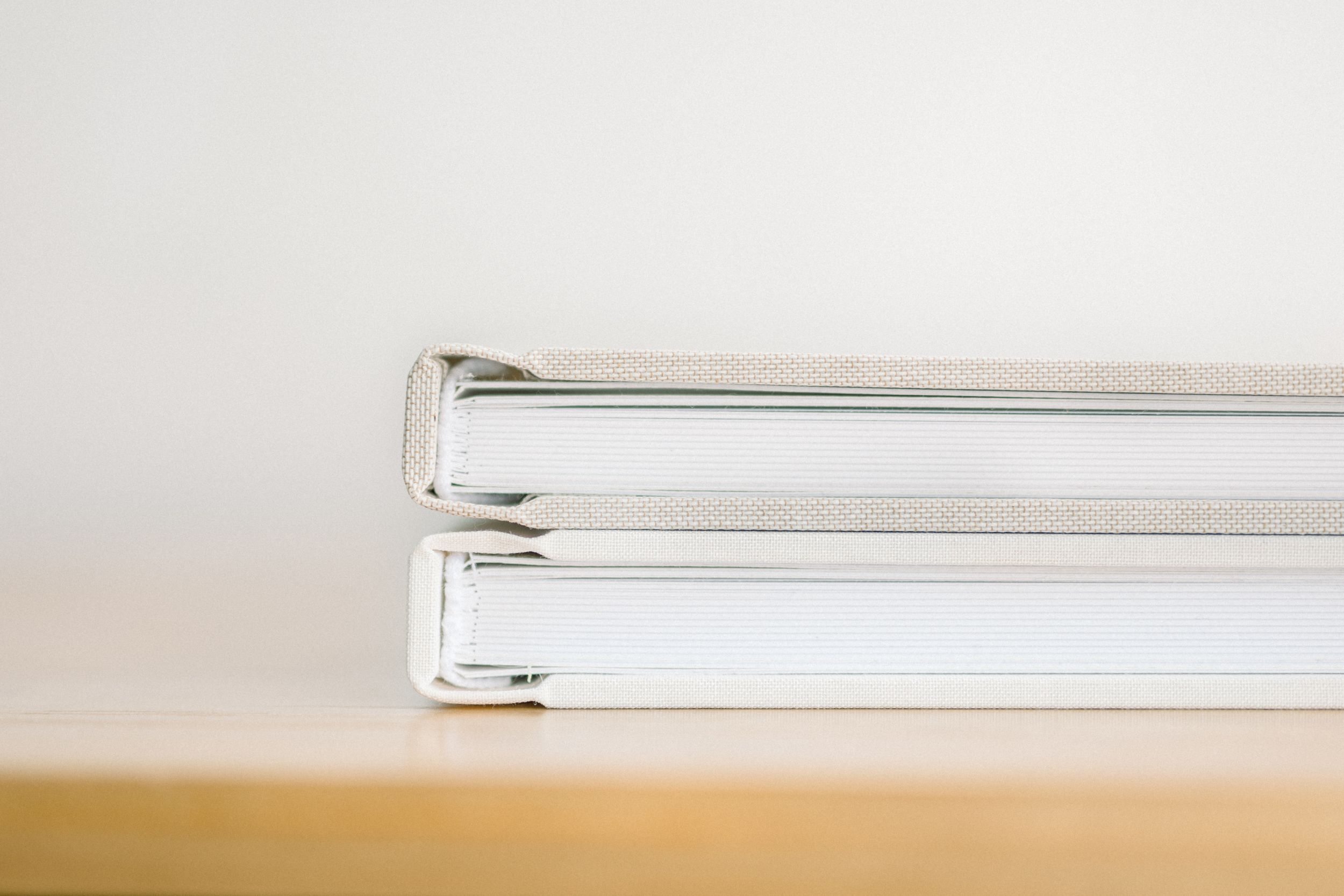 Stack of white photo albums or binders on wooden surface.