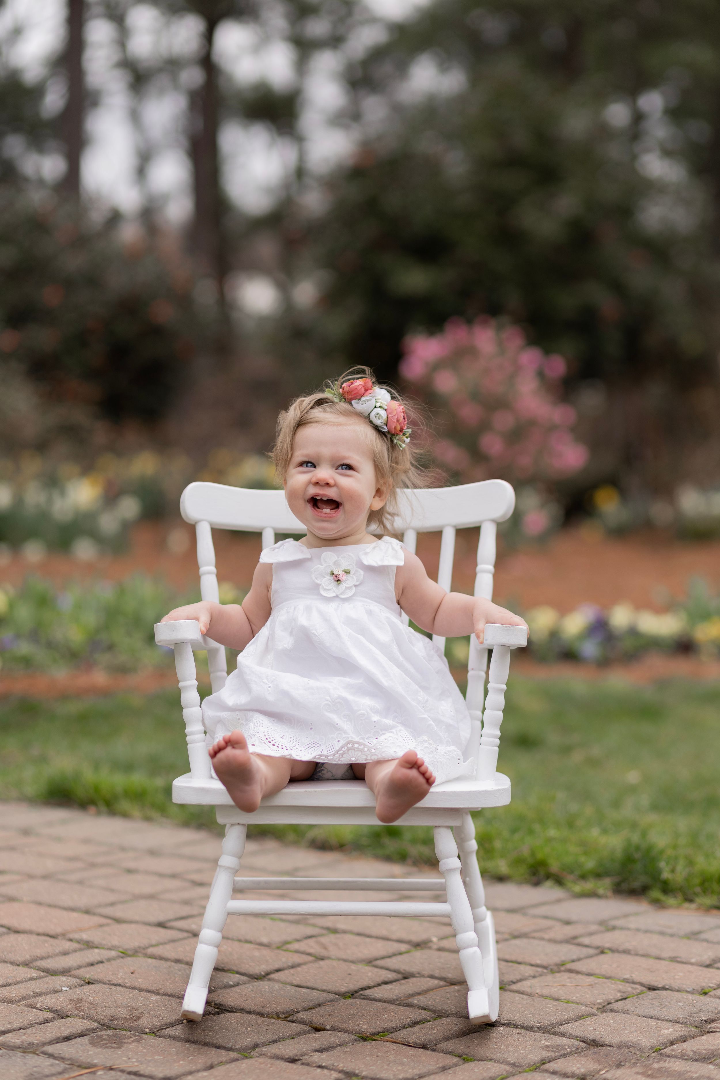 A baby girls sits on white rocking chair at the WRAL Azalea Gardens in Raleigh, NC.