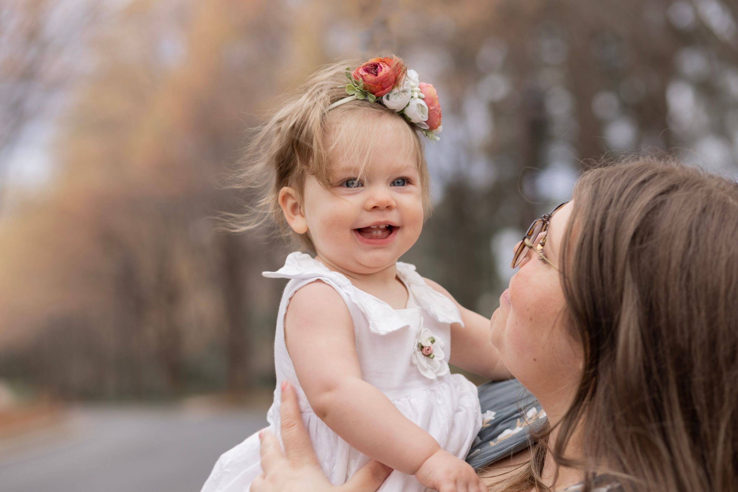 A mom holds up her young daughter at her 1st birthday photoshoot.