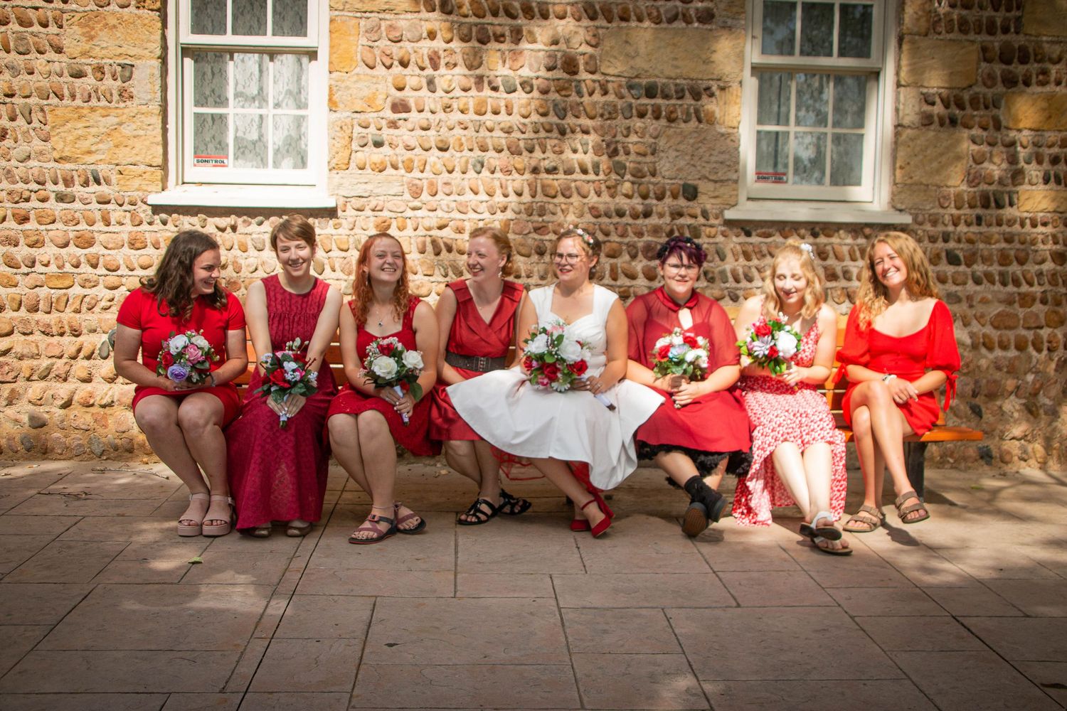 Bride poses on a bench with her bridesmaids