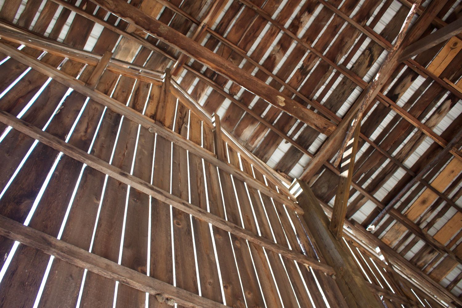view of rustic barn looking up sunshine showing through boards