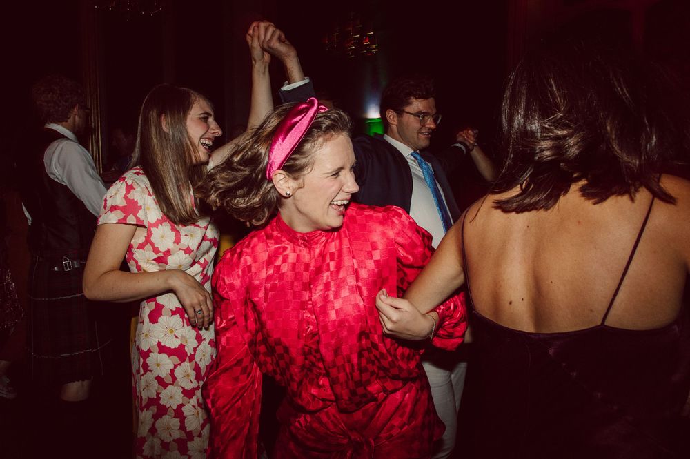 Guests celebrate on the dance floor with one wearing a vibrant red lace dress.