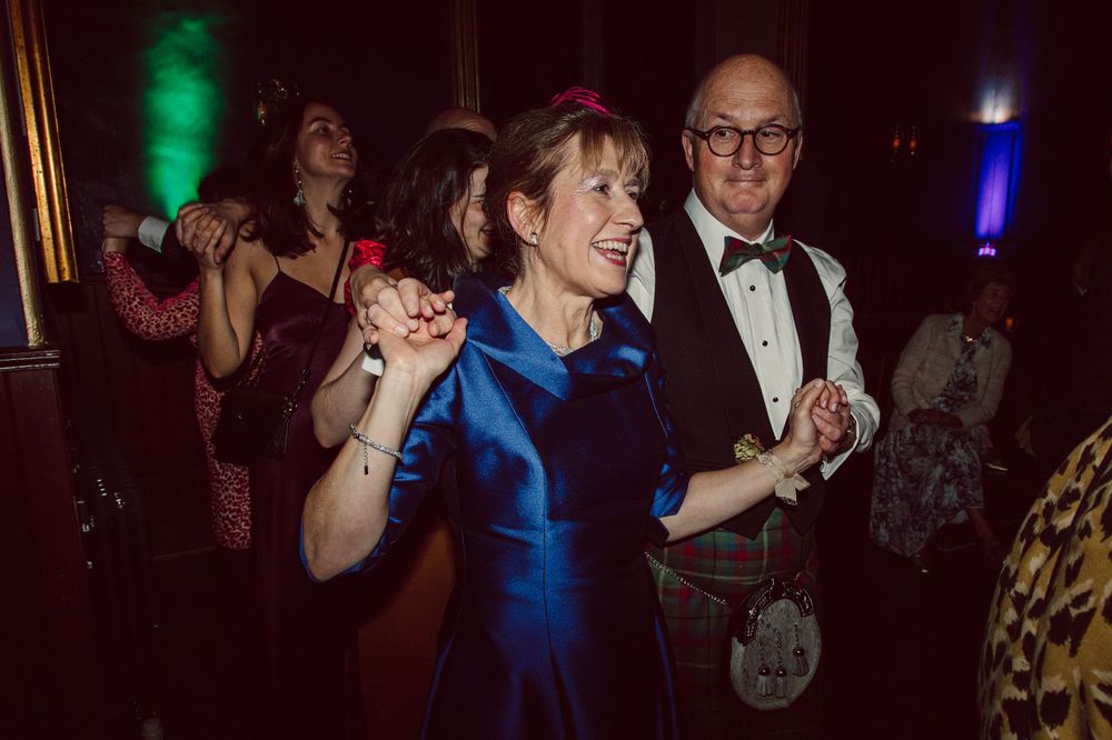 Guests dancing and celebrating at a colorfully lit evening reception party.