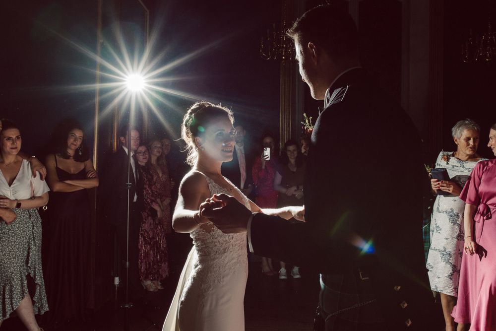 Wedding reception dance floor with dramatic backlighting and dancing silhouettes.