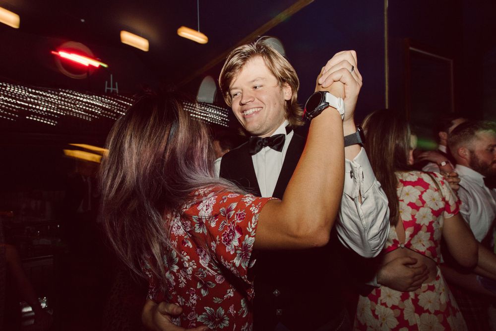 Partygoers dancing under warm lighting at an indoor celebration.