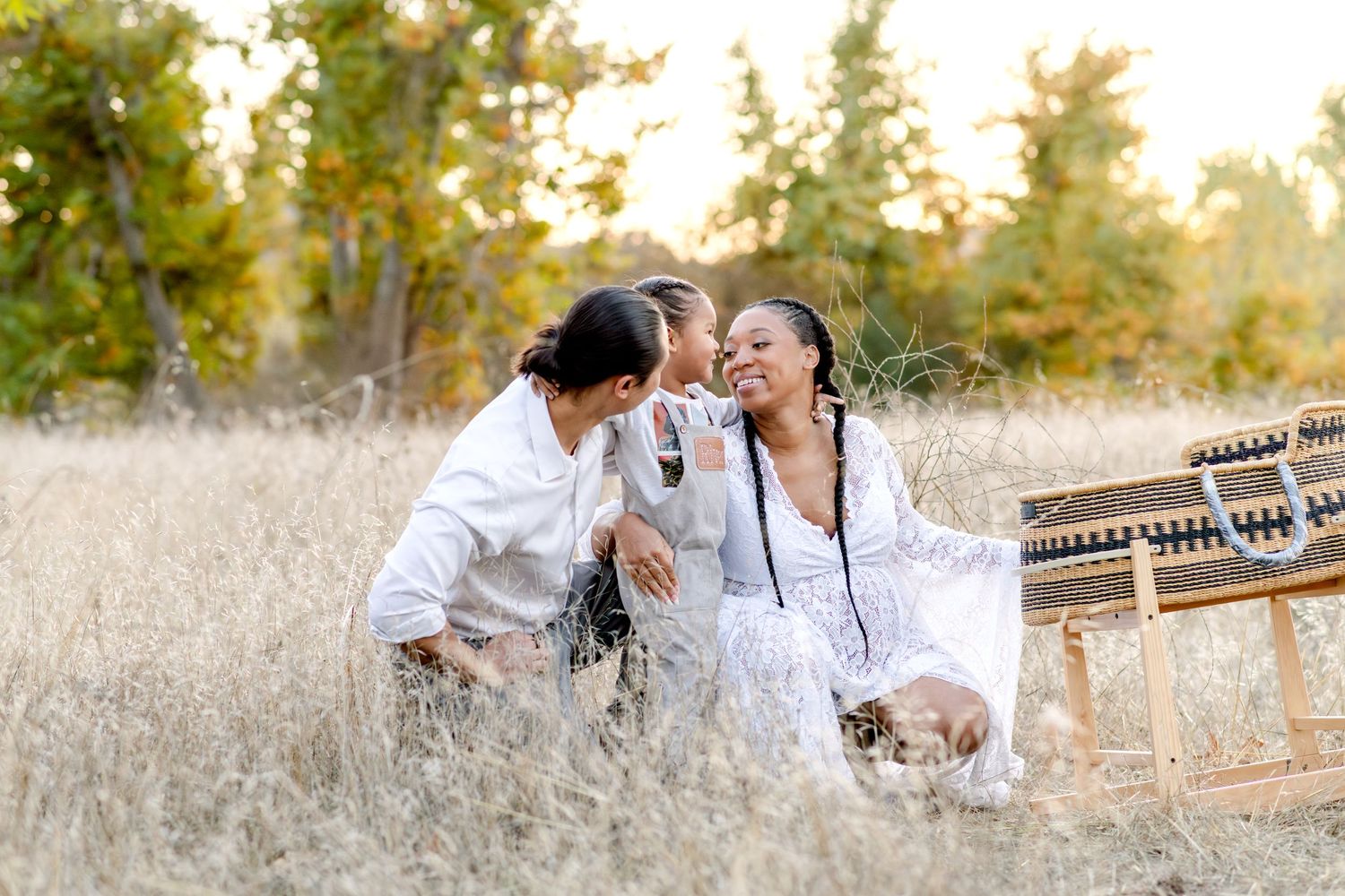 A tender moment shared in a sunlit field with golden grass and trees in the background.